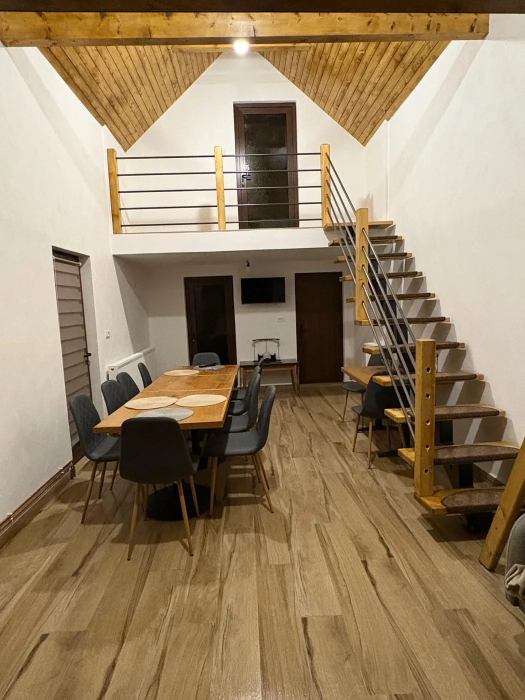 Living spațios cu masă lungă pentru 20 de persoane și scară către mezanin